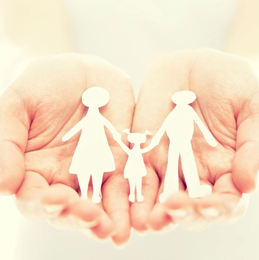 Hands holding paper cutout family figures.