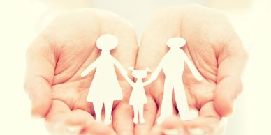A pair of hands holding a paper cutout of mother, father, and child