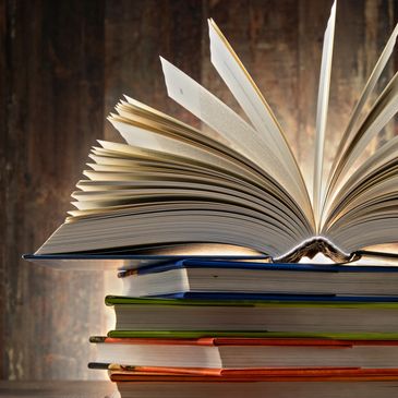 Color photo of a stack of books, with one book wide open on top