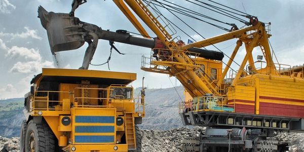 Large yellow excavator loading a dump truck at a mining site.