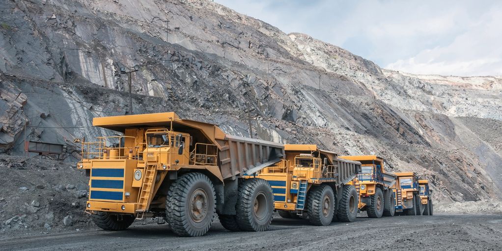 Large mining trucks lined up at a rocky quarry.