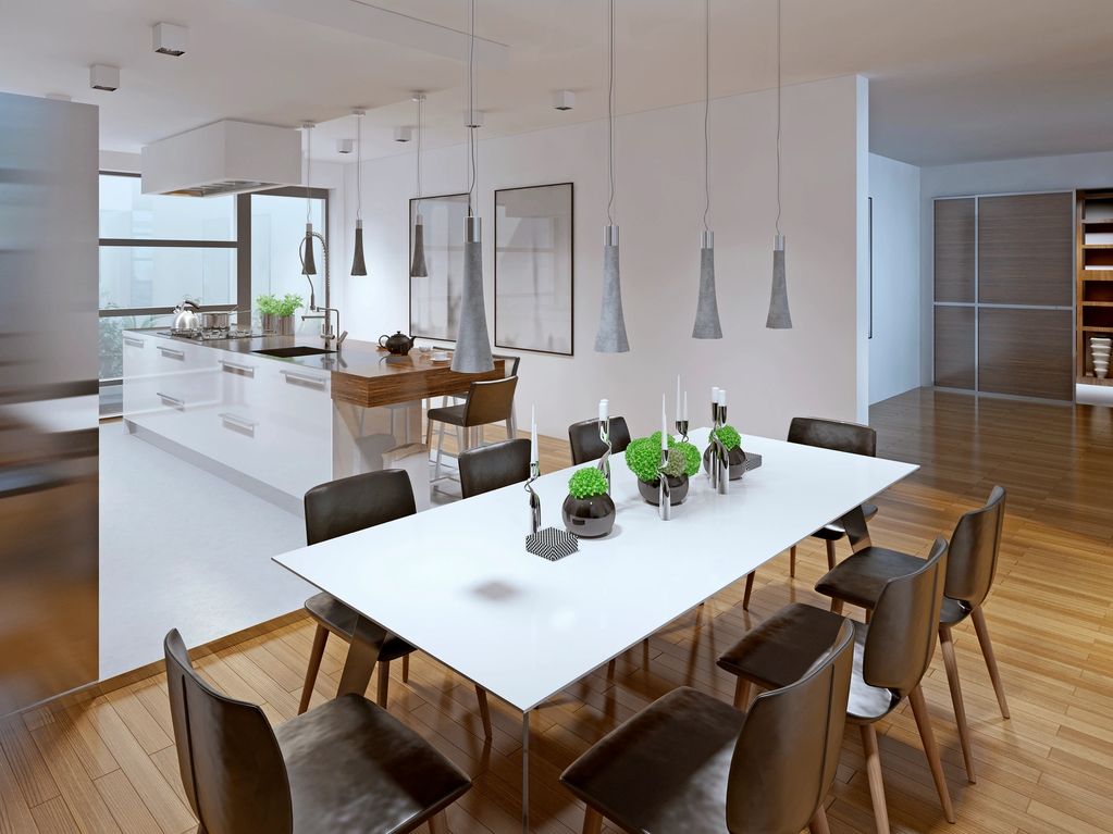 Modern dining room with sleek white table and black chairs under pendant lights.