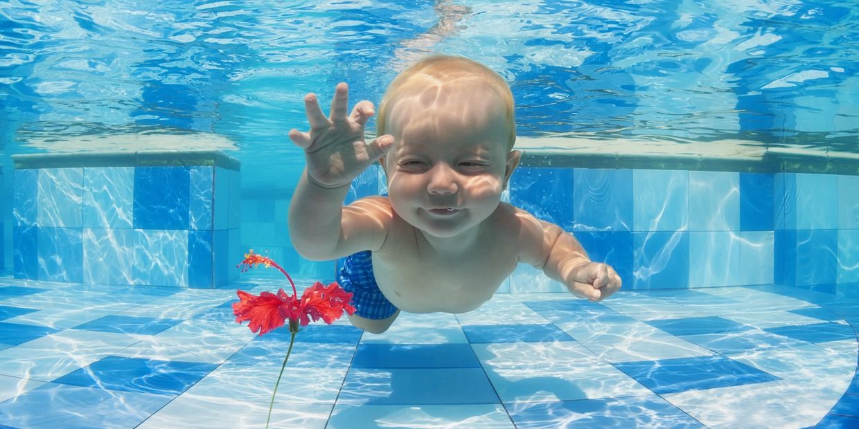 Baby underwater in the pool waving hello with eyes closed!
