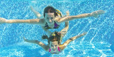 Girls swimming in pool, holding their breath underwater.