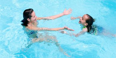 Young girl swimming in pool with instructor.