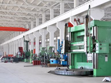 A spacious industrial factory with large green machines lined up.