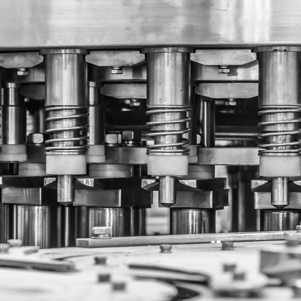 Close-up of stainless steel industrial machinery with springs and pistons.