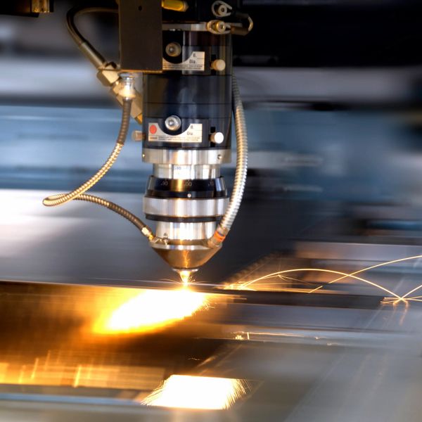 A laser cutting machine slicing through metal with bright sparks.