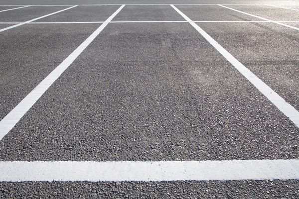 Empty asphalt parking lot with white painted lines.
