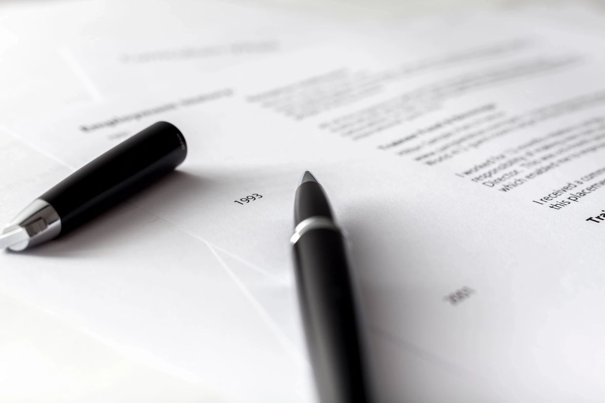 A close-up of a resume with a pen on top of it. 
