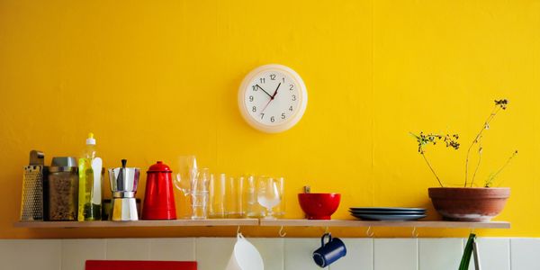 A clock on the wall above a kitchen counter.