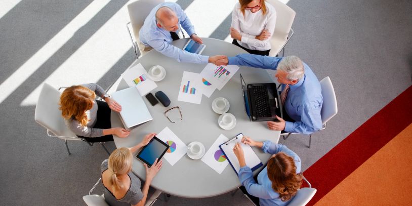 Business meeting with professionals discussing charts and shaking hands.