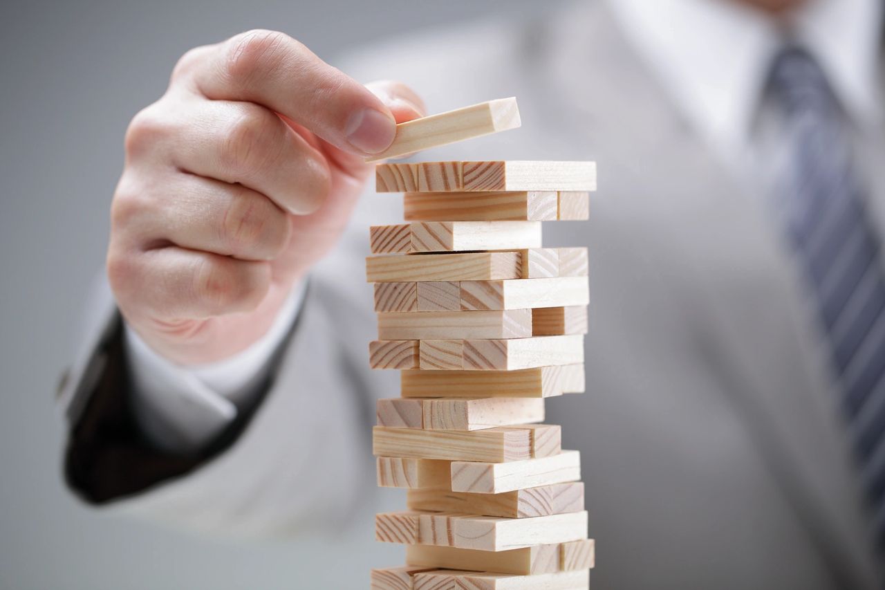 A person places a wood piece atop other pieces in a game of jenga.