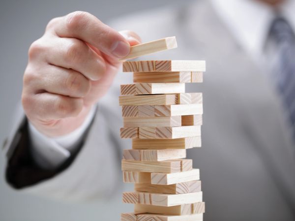 Hand placing a wooden block on Jenga tower.