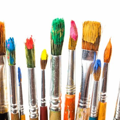 Variety of paintbrushes with colorful paint on tips.