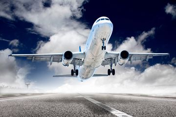A commercial airplane takes off from a runway under a cloudy sky.