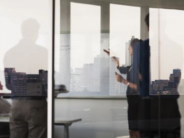 Business professionals discussing strategy by a window with city view.