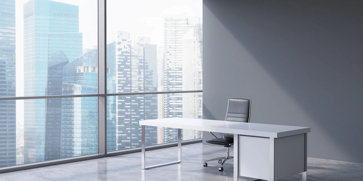 Modern office with a white desk and black chair by a large window overlooking city skyscrapers.