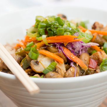 Colorful vegetable stir-fry with green onions and carrots in a white bowl.