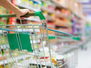 A woman pushing a green shopping cart in the store