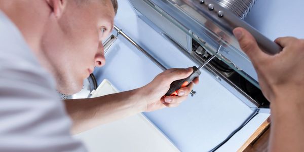 Repair person fixing hood fan