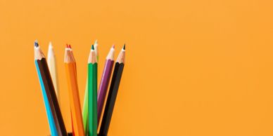 Colored pencils arranged against an orange background.