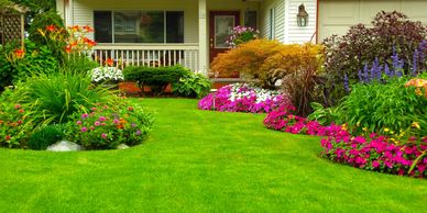 Font yard with a lush, evenly mowed lawn and a vibrant flower bed along the left side.