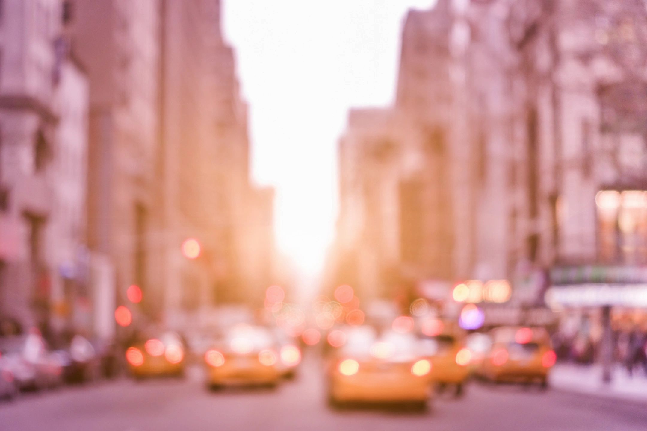 A blurry picture of a city street with taxis driving down it.