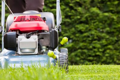 man pushing a lawn mower cutting green grass