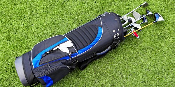 Golf clubs in a golf bag lying on the green. 