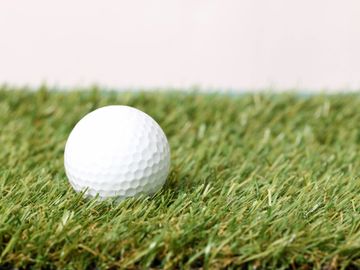 Close-up of a white golf ball on green grass.