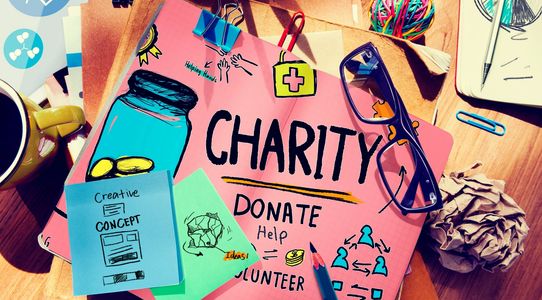 A work desk is covered with sketches of concepts, with the words "charity"  at the center.