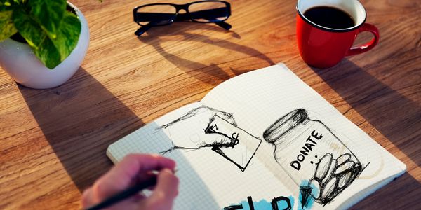 a notebook with donate drawing and a cup 