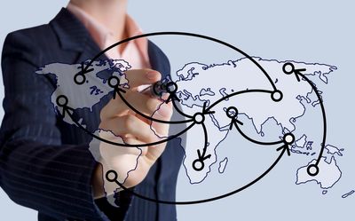 Businessman drawing global network connections on transparent world map.