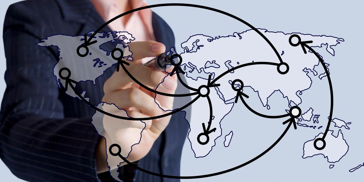 Person drawing global network connections on a world map.