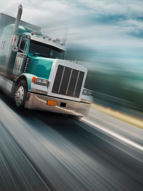 A green semi-truck speeding down the highway.