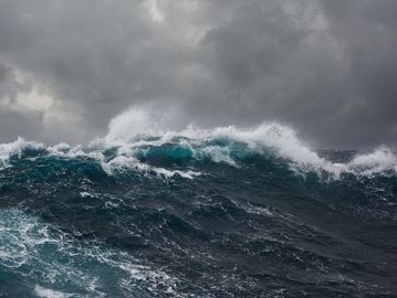 Dark stormy ocean waves crashing under a cloudy sky.