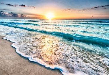 Sunset over the ocean with waves gently hitting the shore.