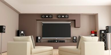 Modern home theater setup with beige sofas and surround sound speakers.