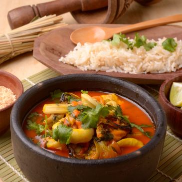 Spicy vegetable stew with rice served on a wooden plate.