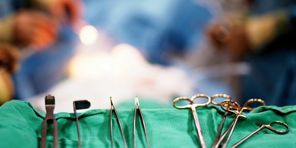 Surgical instruments laid out on a green cloth in an operating room.