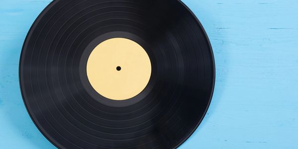 Black vinyl record with a blank beige label on a blue wooden surface.