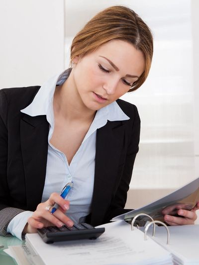 Businesswoman calculating finances with documents and calculator.