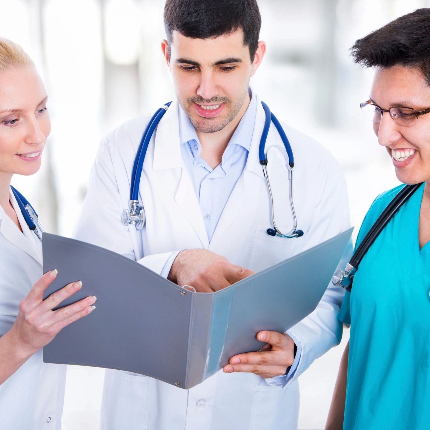 Three doctors reviewing medical files together in a hospital.