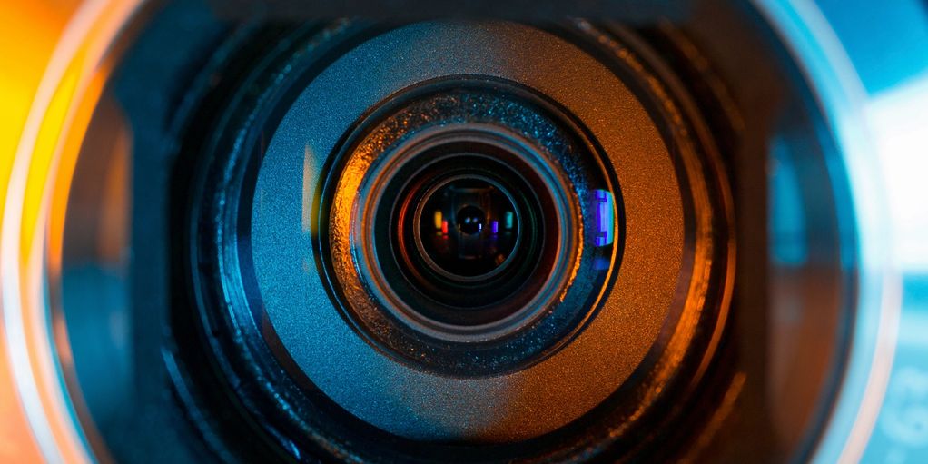 Close-up of a camera lens with blue and orange lighting.
