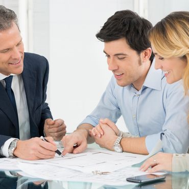 Three professionals discussing documents around a glass table.