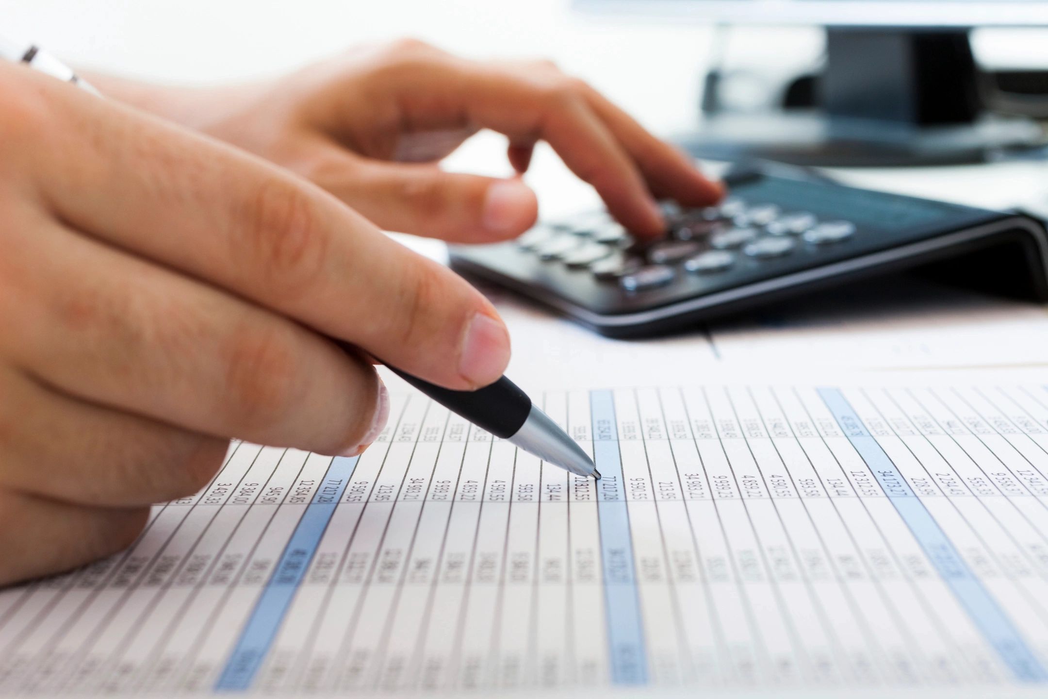 A person is using a calculator while holding a pen