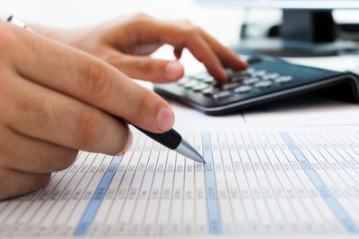 A person using a calculator and pen, marking something on a document