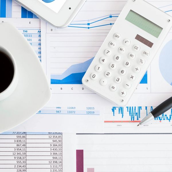 Workspace with calculator, coffee, pen, and financial charts.