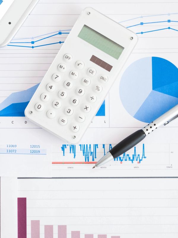 Calculator and pen on financial charts with coffee.